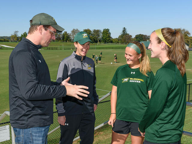 Chemistry professor Dana Ferraris, faculty athletics mentor to the women's soccer team, explains to coach Sandy Lagana and team co-captains Abby Keen and Kristen Upton how he and his wife make the bagels he brings to the team on home-game mornings.