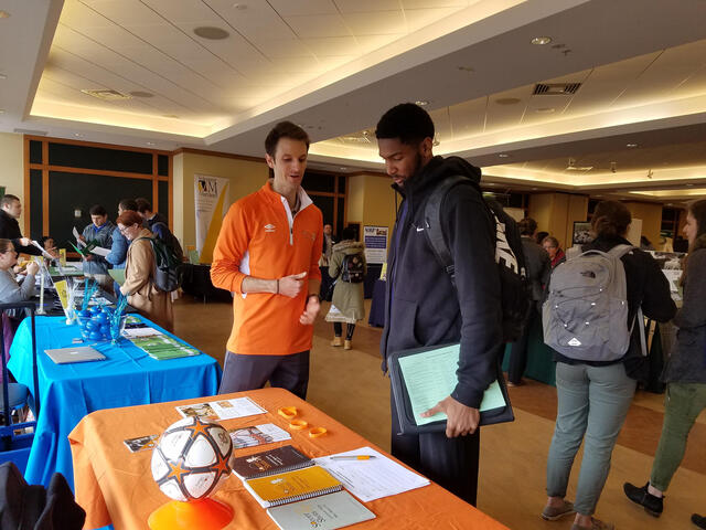 An employer talks to students at a job and internship fair. 