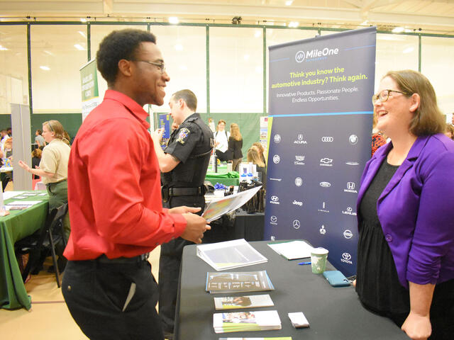 An employer talks to students at a job and internship fair. 