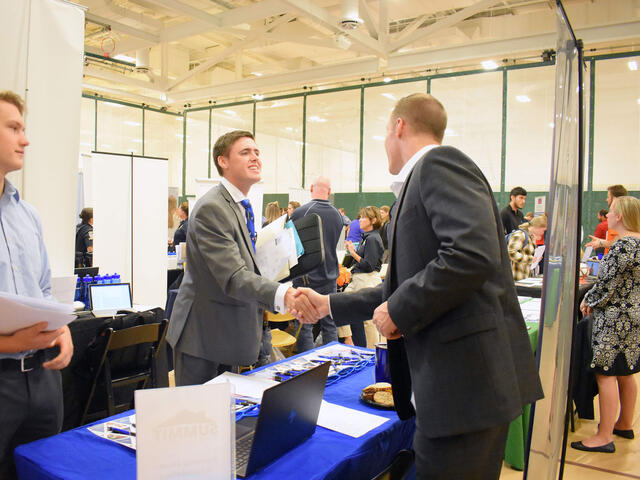 An employer talks to students at a job and internship fair.