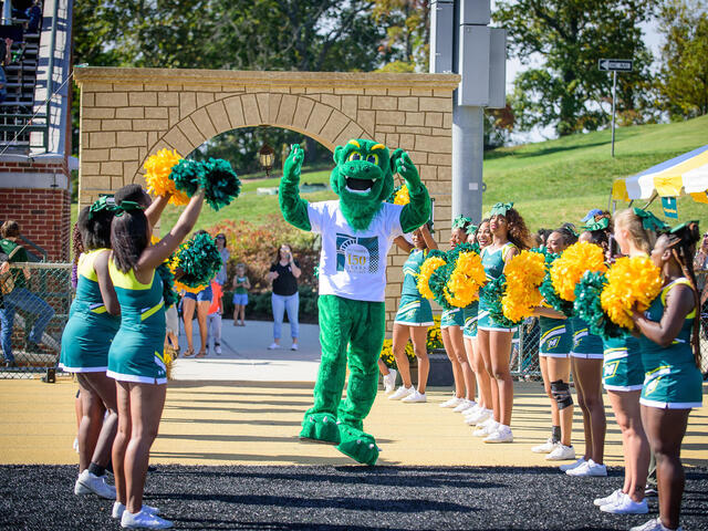 Green Terror mascot with cheerleaders.