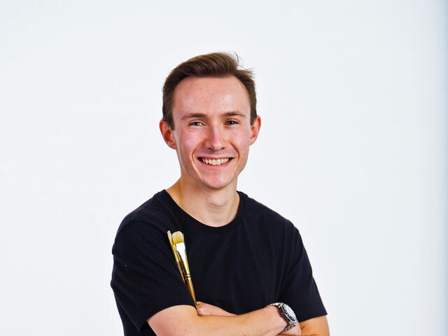 Jonathan Nepini holding paint brushes.