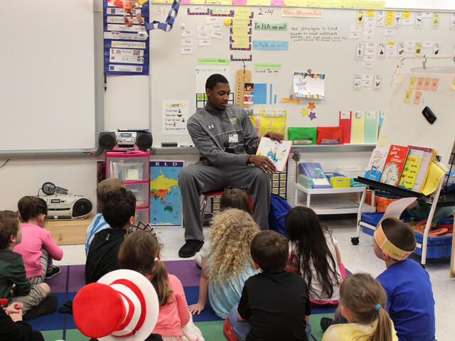 Student reading to a classroom full of elementary school children.