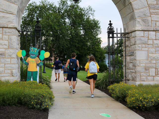 students walk under arch, past the Green Terror