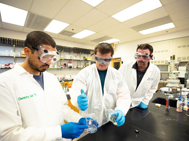 students with professor in chemistry lab