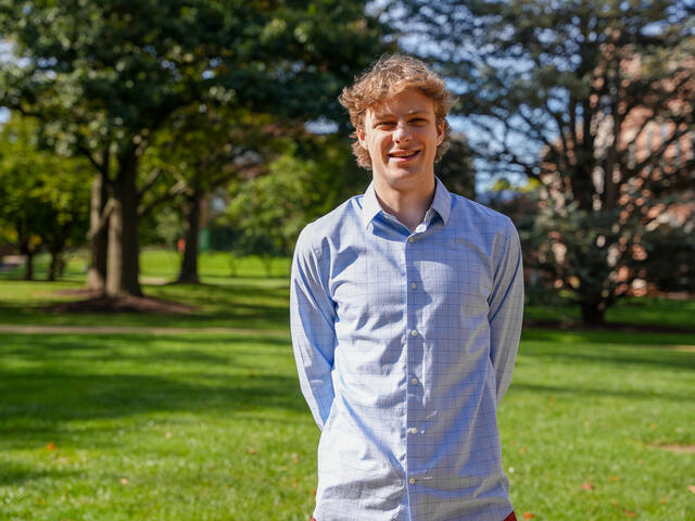 Alum Dominic Byerly posing in a green field.