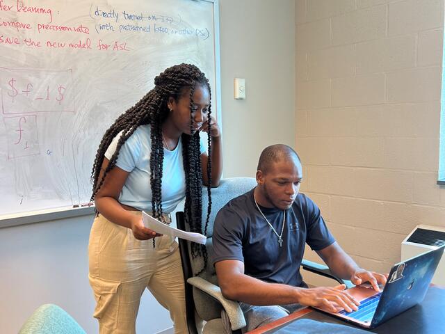 Two students collaborate at a computer.