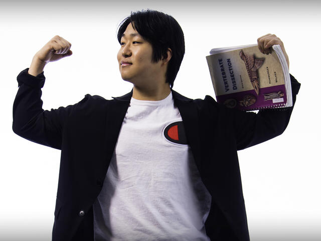 Headshot of Hyosik Kim holding a textbook.