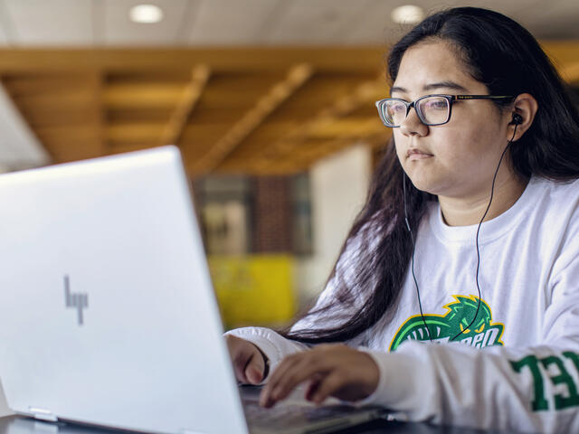 student typing on her laptop