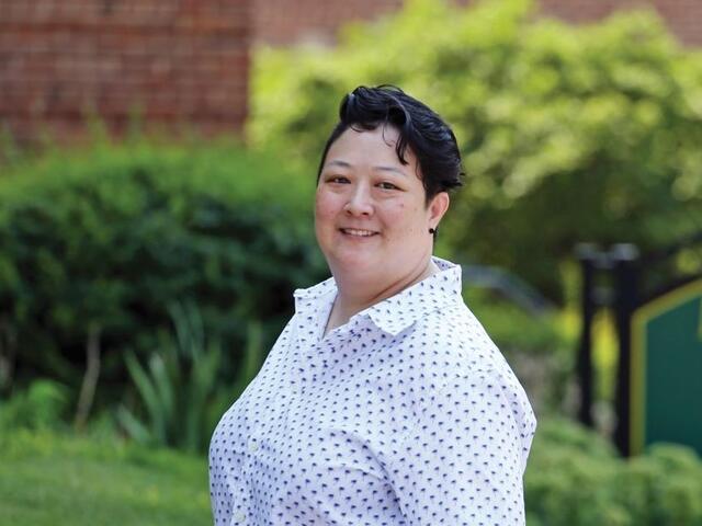 Photo of professor Shana Joslyn standing outdoors in front of green bushes.