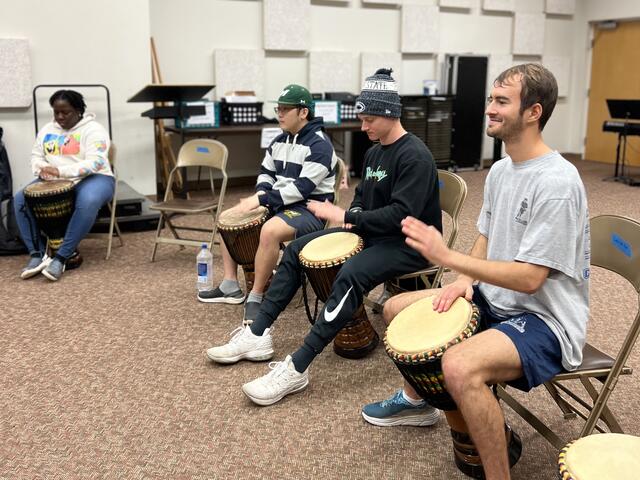 Photo of students playing drums in a classroom.