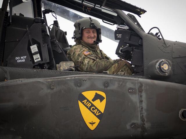 Alum Zach Nibbelink looks at the camera while sitting in an Apache helicopter cockpit.