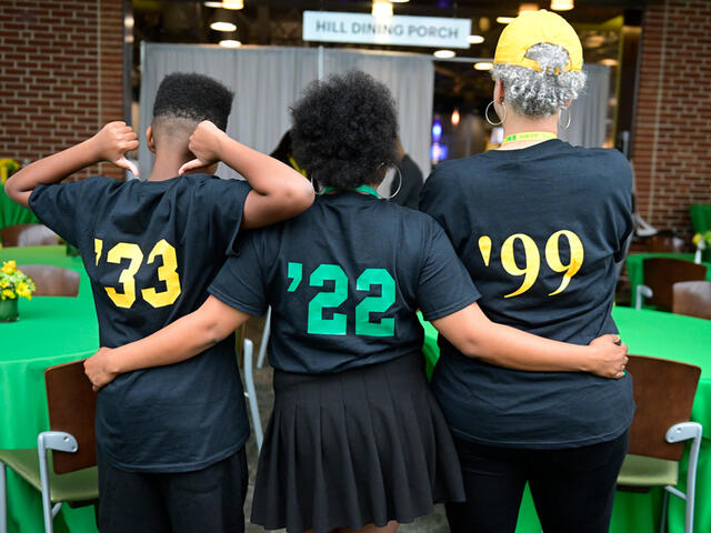 Two alums and a future alum showing off the grad years on the back of their shirts.