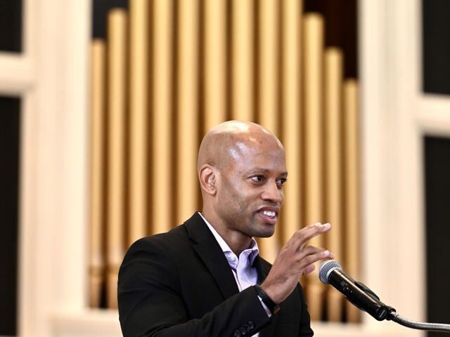 College Chaplain, Richard Smith ’00, Ph.D. speaks at a podium in front of organ pipes