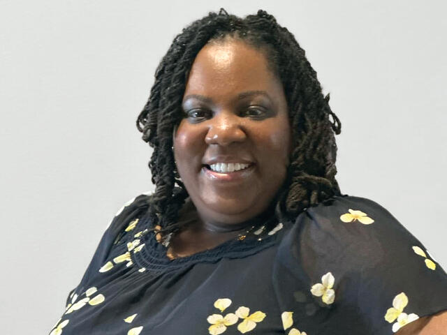 Rosalyn Davis smiles while wearing a black blouse with yellow flowers on it.