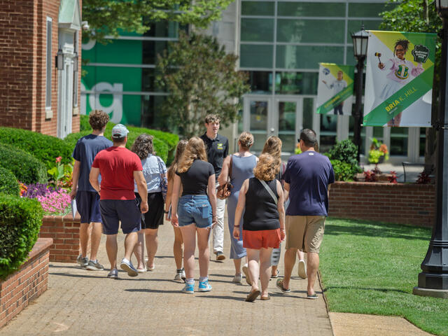 a student walks backwards, talking to a group of people while giving a tour of campus