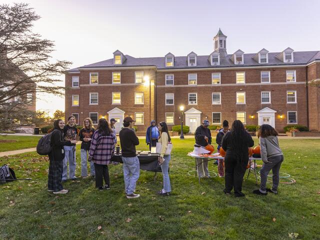 students gather around a table carving pumpkins at Halloween time