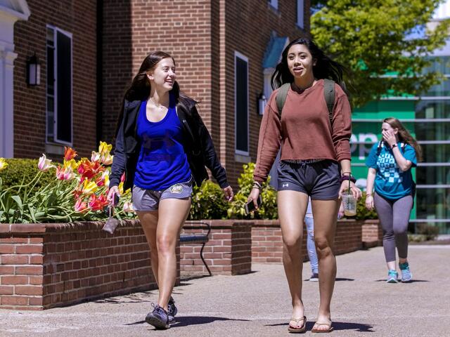two female students walking on college campus in spring
