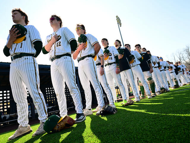 baseball stands for the anthem during pregame festivities.