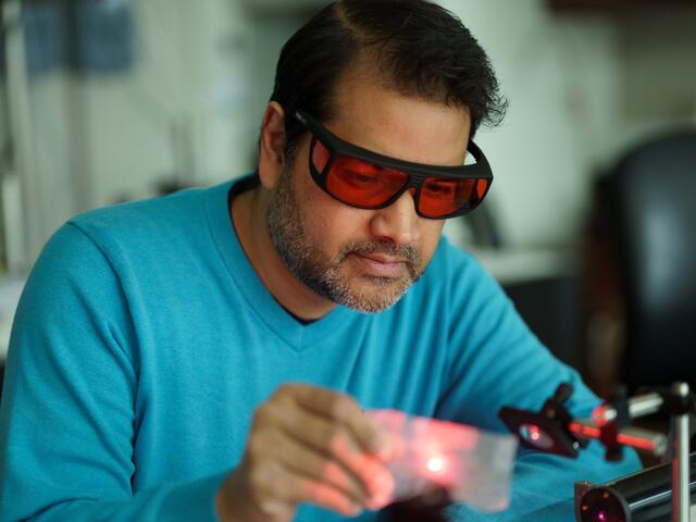 An Engineering professor experiments with lasers in a lab.