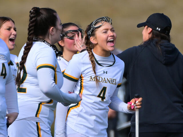 women's lacrosse sideline celebrates a big play.
