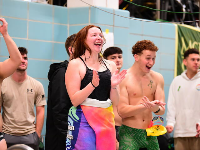 Men's and women's swimmers celebrate poolside.