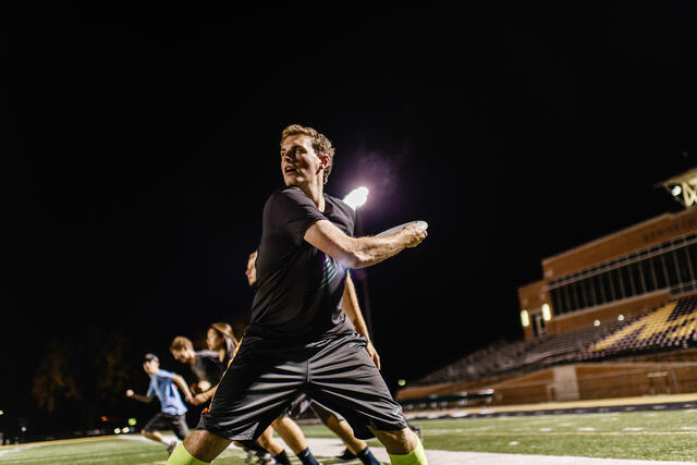 Student playing frisbee on football field.