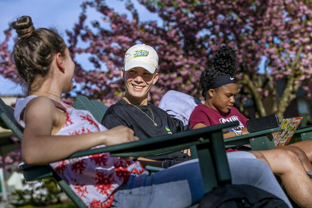 Students sitting in outdoor chairs on campus.