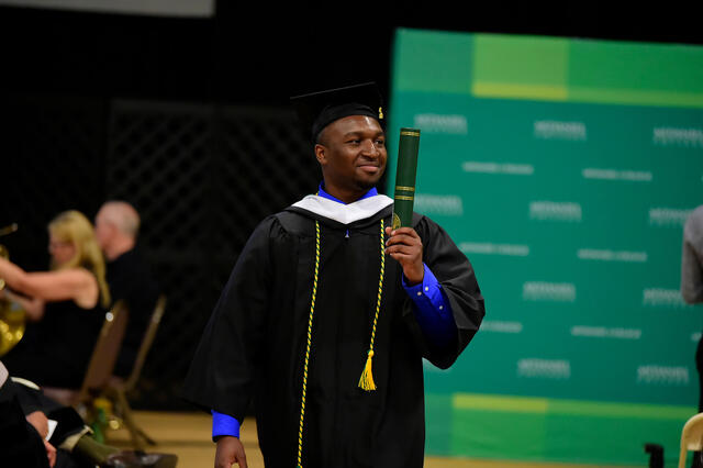 Student with diploma in hand at Commencement 2019.