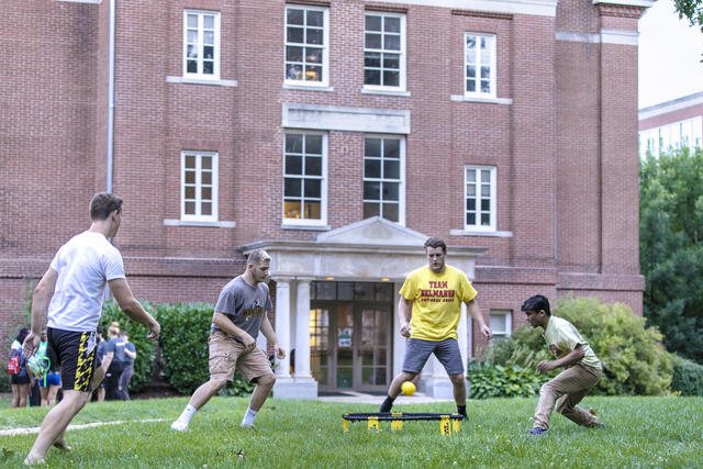 Students playing Spikeball on campus lawn.