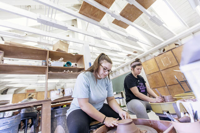 Art students throwing pottery on pottery wheels.