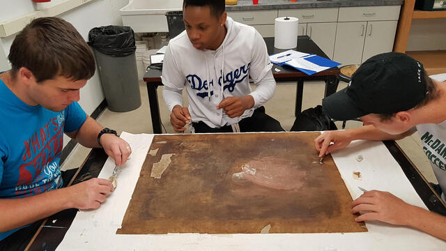 Students work on fitting the inserts and filling in the gaps with canvas fluff to even out the surface before relining.
