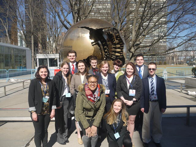 students pose in front of statue