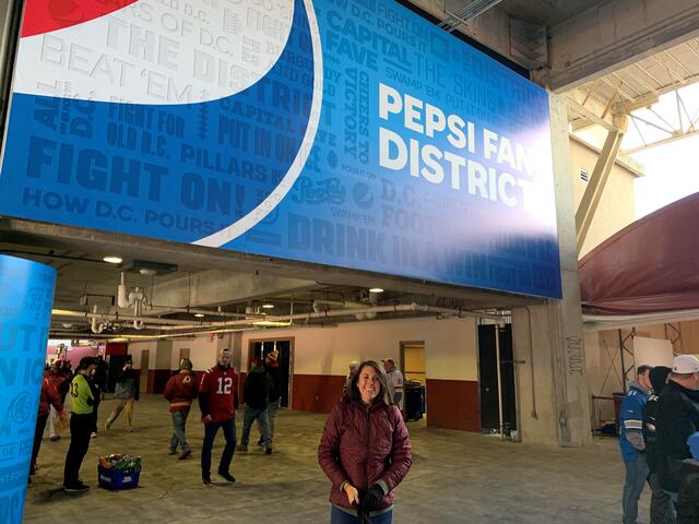 Alumna Lauren Avery standing in the Pepsi fan district she designed at FedEx Field.