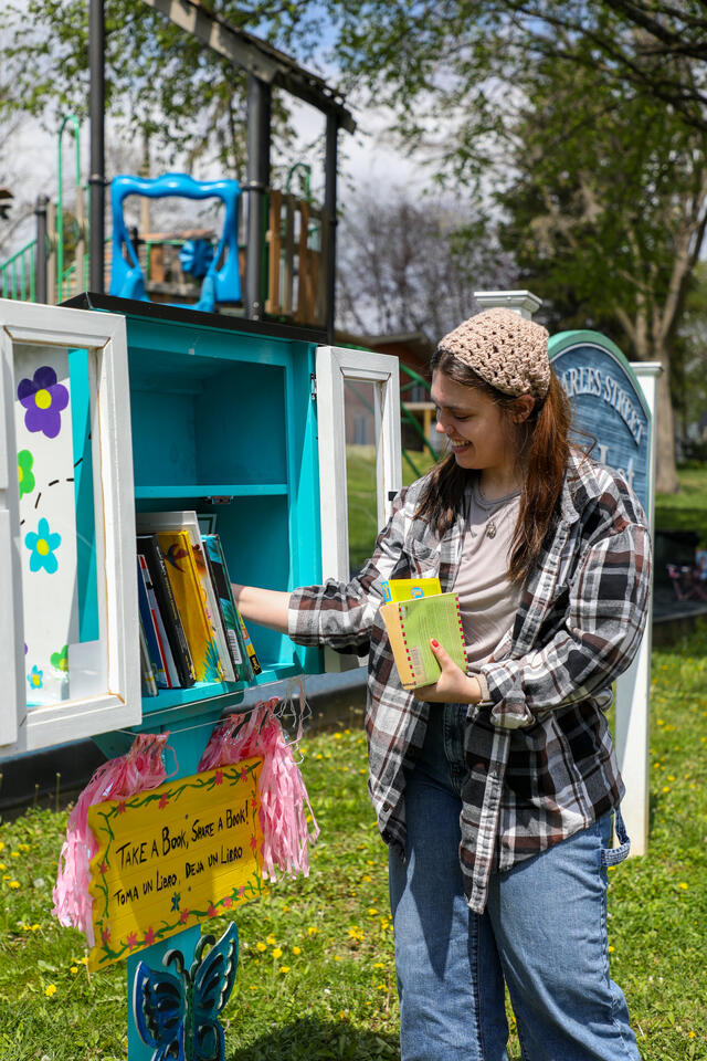 Student Gia K. places books into her new little free library.