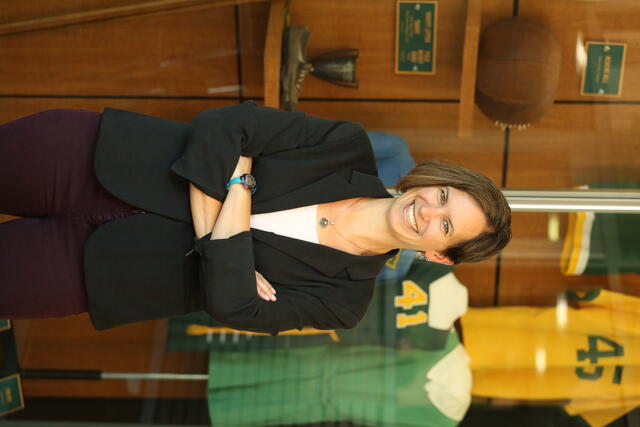 Professor Diane Williams poses in front of vintage McDaniel sports uniforms.