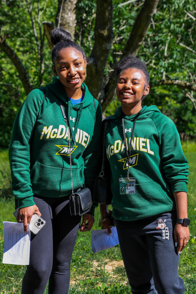 Two students pose in matching green McDaniel sweatshirts.