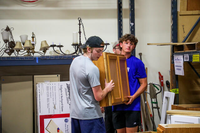 Two students carry a cabinet at Habitat for Humanity Restore.
