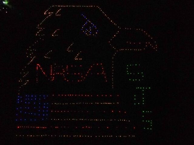 Aerial image at night of an eagle design in a field lit up by lights.