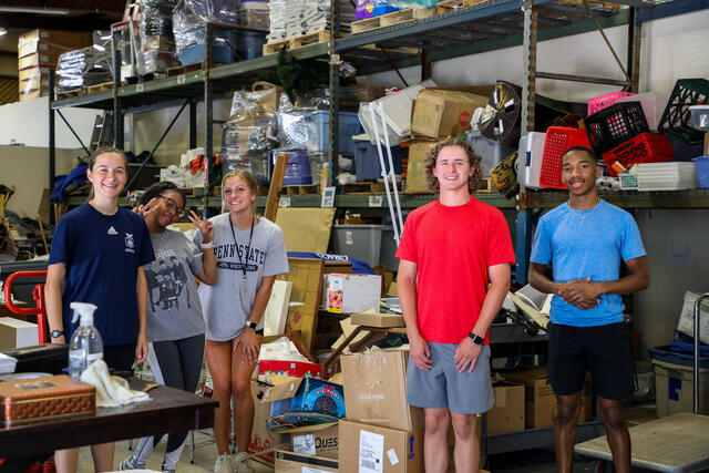 Five students pose in the Habitat for Humanity ReStore warehouse.