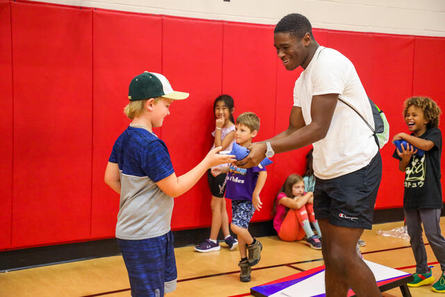 A students hands a child a beanbag at the Boys and Girls Club of Westminster.