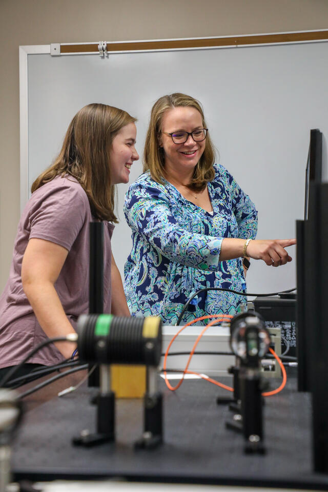 Student Hailey Perry looks at a computer with professor Stephanie Homan.