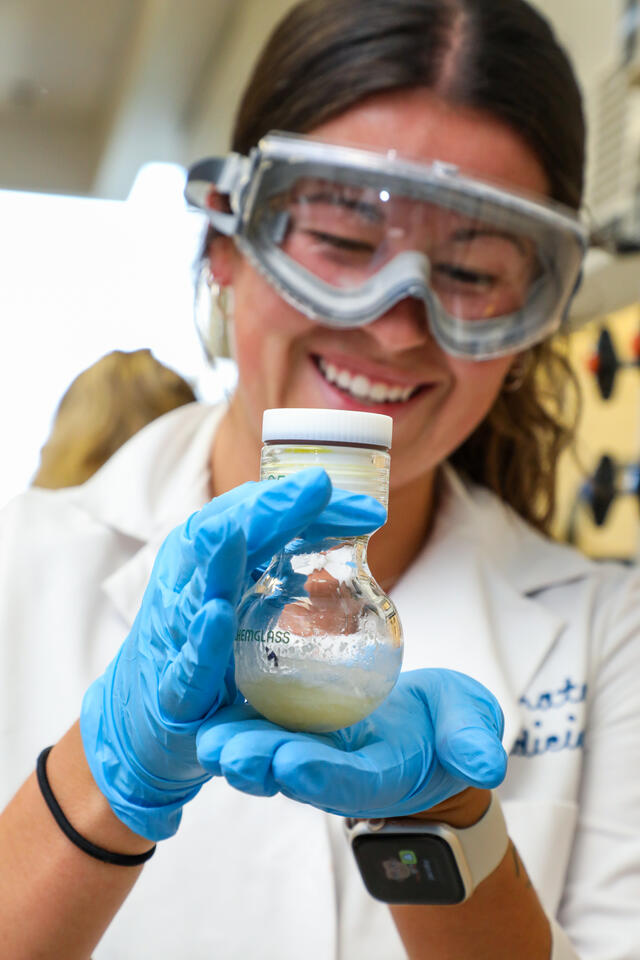 A student holds up a beaker of solution.