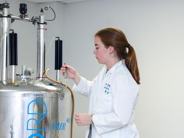 A student uses the NMR machine to test a compound.