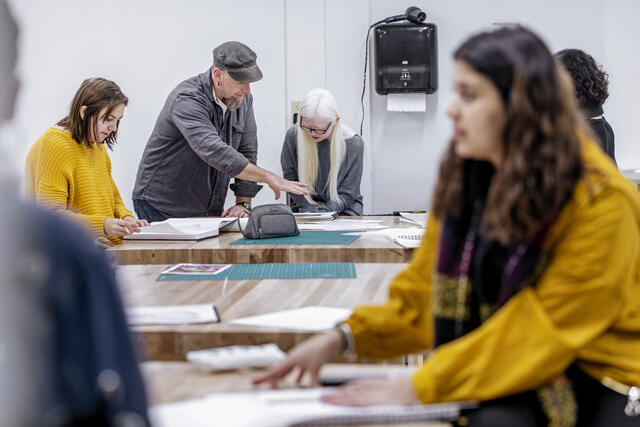 Students and faculty working at art studio tables.