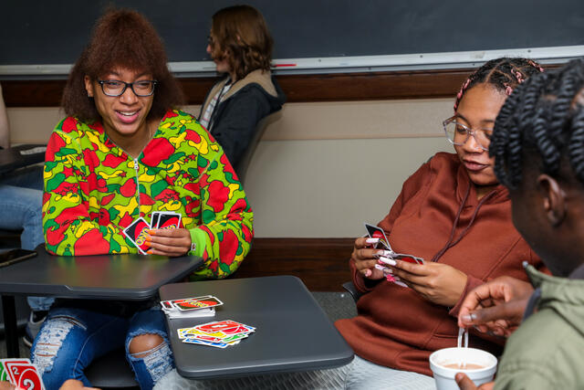 Three students play a game of UNO in class.