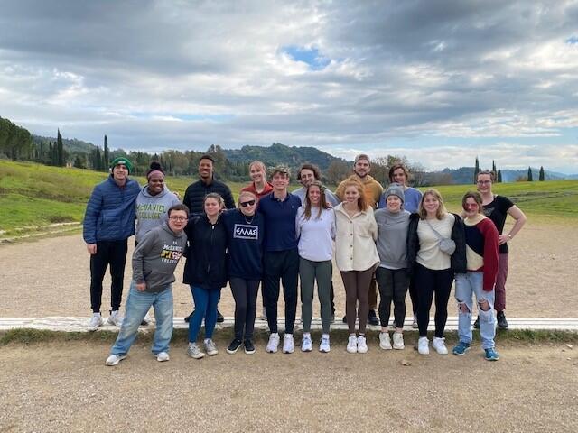 Students stand together in a field in Greece 