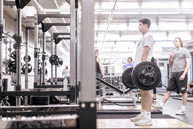 A student performs a deadlift with a barbell in Merritt Fitness Center.
