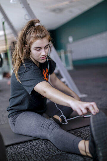 A female student stretches her legs on a mat in Merritt Fitness Center.