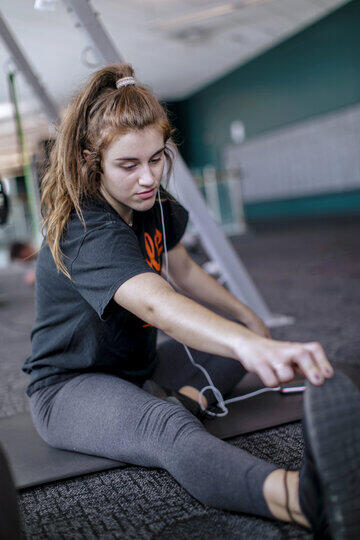 A female student stretches her legs on a mat in Merritt Fitness Center.